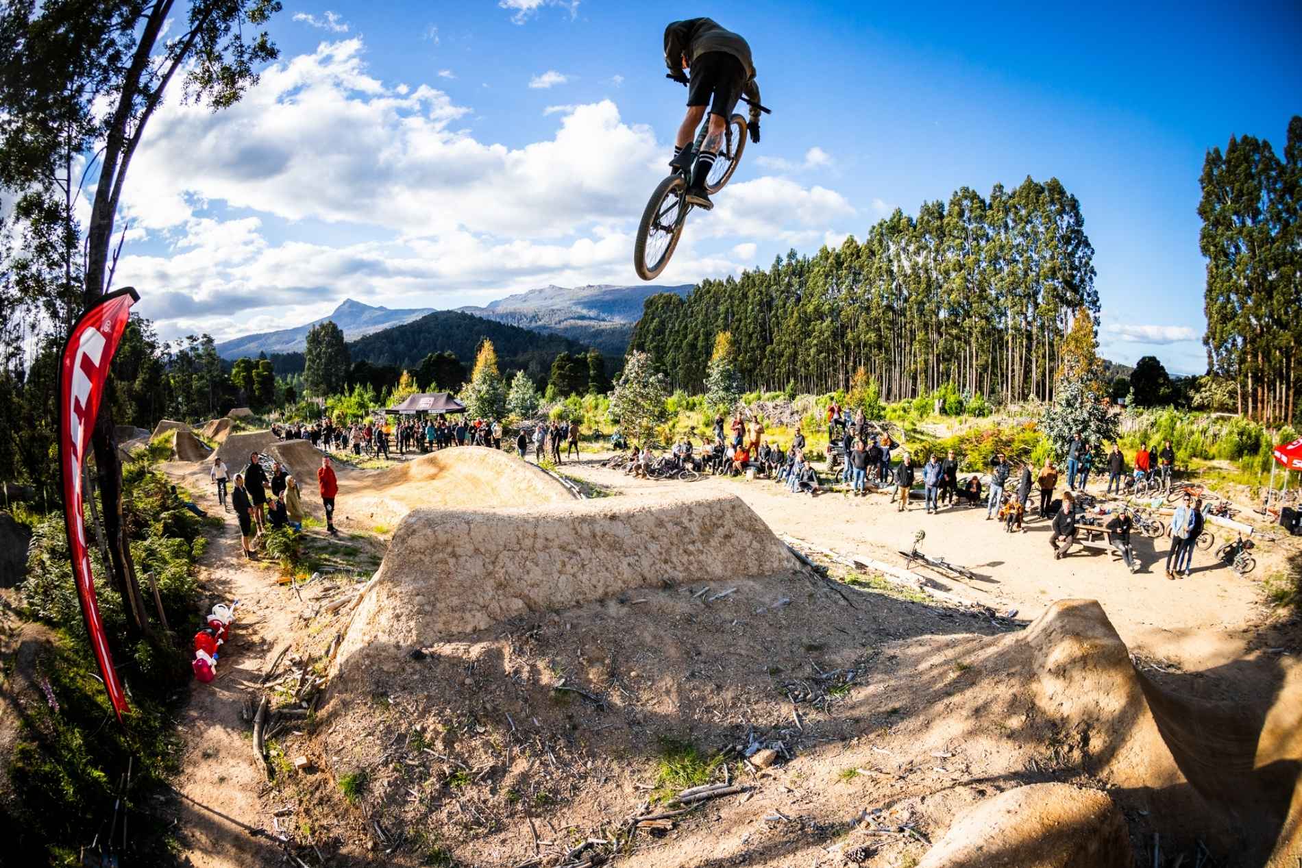 Bike rider jumping in air between jumps performing a trick in the air at maydena bike park