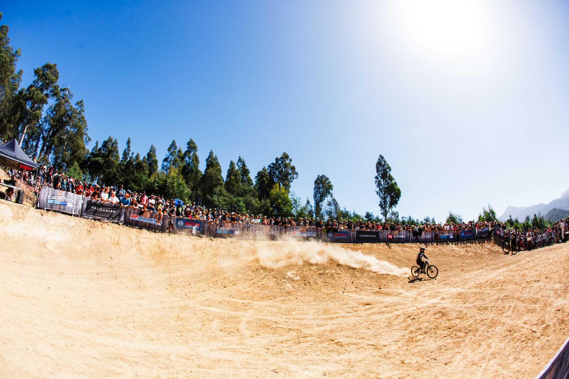 Rider with sponsor signs riding dusty park bowl - wide shot